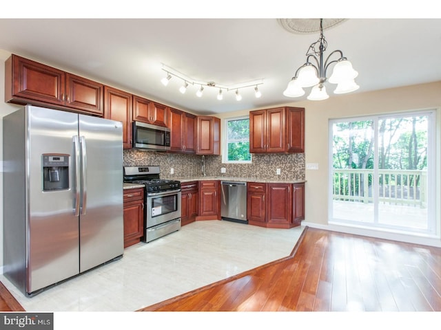 kitchen with an inviting chandelier, decorative light fixtures, light hardwood / wood-style flooring, stainless steel appliances, and backsplash