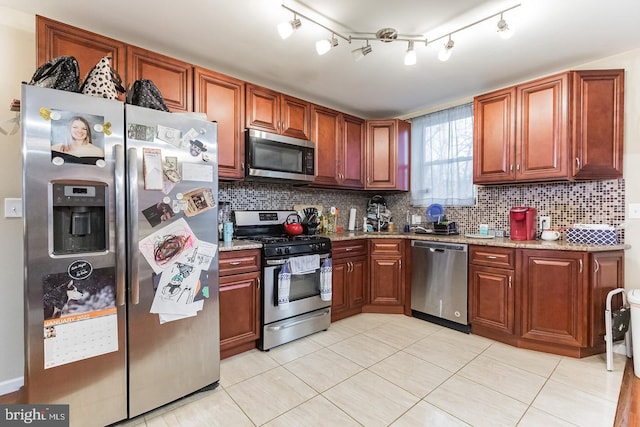 kitchen featuring tasteful backsplash, stainless steel appliances, light stone countertops, and light tile patterned flooring