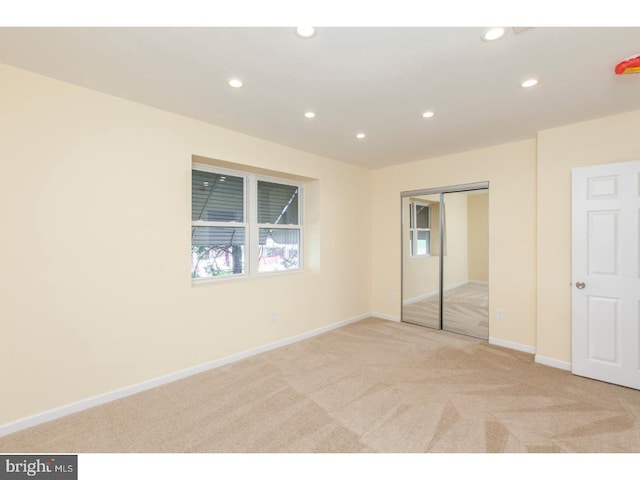 unfurnished bedroom featuring light colored carpet and a closet