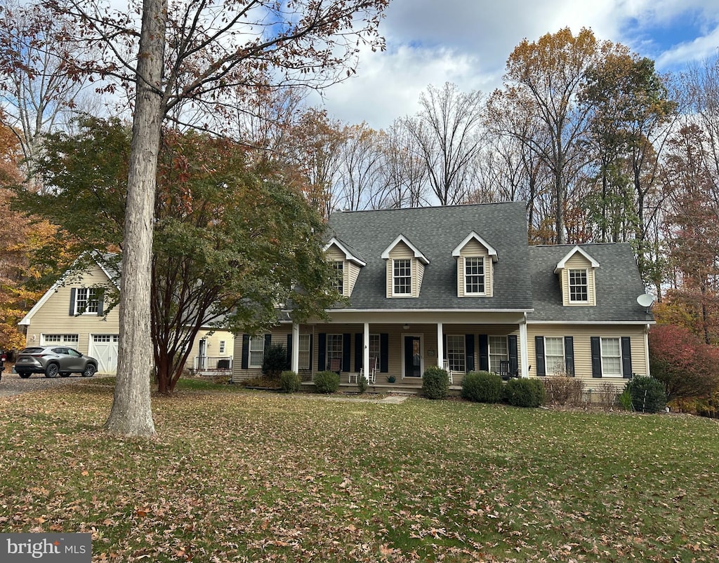 cape cod home featuring a porch, a front lawn, a shingled roof, and a detached garage