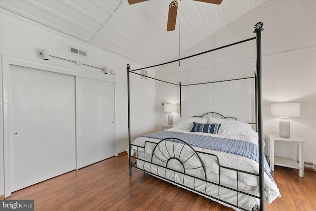 bedroom featuring lofted ceiling with beams, wood ceiling, ceiling fan, dark wood-type flooring, and a closet