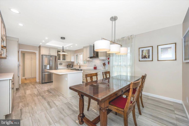 dining room with baseboards, a raised ceiling, and recessed lighting