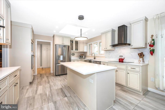 kitchen featuring stainless steel appliances, a kitchen island, light countertops, wall chimney exhaust hood, and tasteful backsplash