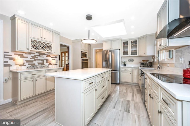 kitchen featuring a kitchen island, a sink, appliances with stainless steel finishes, decorative backsplash, and wall chimney exhaust hood