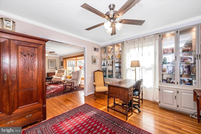 office with visible vents, light wood-style floors, a ceiling fan, and crown molding