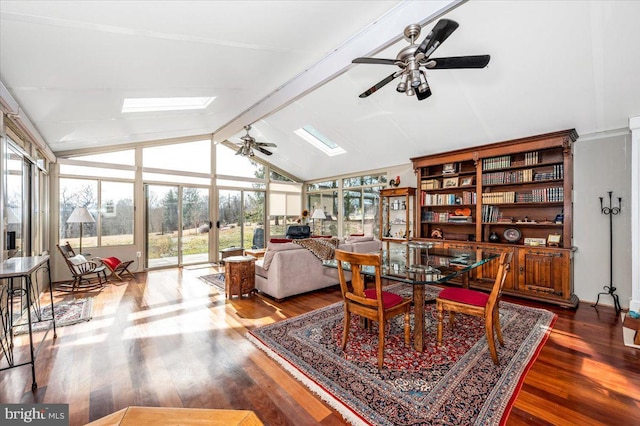 interior space featuring a ceiling fan, vaulted ceiling with skylight, a healthy amount of sunlight, and wood finished floors