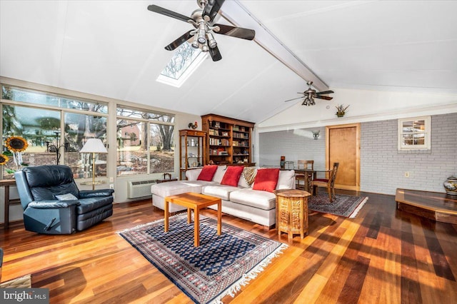 living room with a wall unit AC, lofted ceiling with skylight, a ceiling fan, brick wall, and wood finished floors