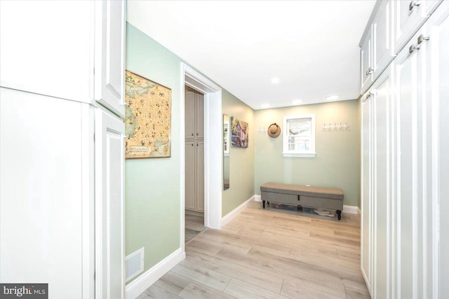 hallway featuring light wood-style flooring, visible vents, and baseboards