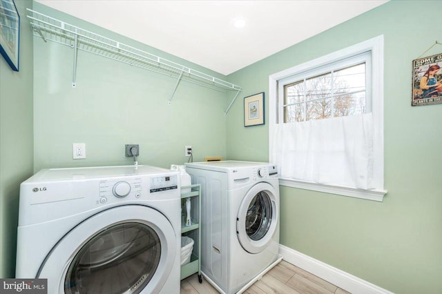 laundry area with baseboards, laundry area, light wood-style floors, and washer and dryer