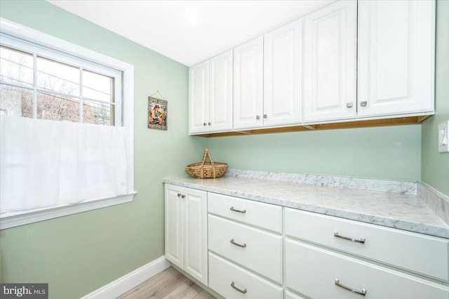 laundry area with light wood-type flooring and baseboards