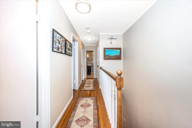 hall with ornamental molding, baseboards, an upstairs landing, and wood finished floors