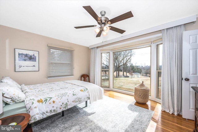 bedroom with a ceiling fan, access to outside, and wood finished floors