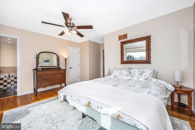 bedroom with a ceiling fan, visible vents, baseboards, and wood finished floors