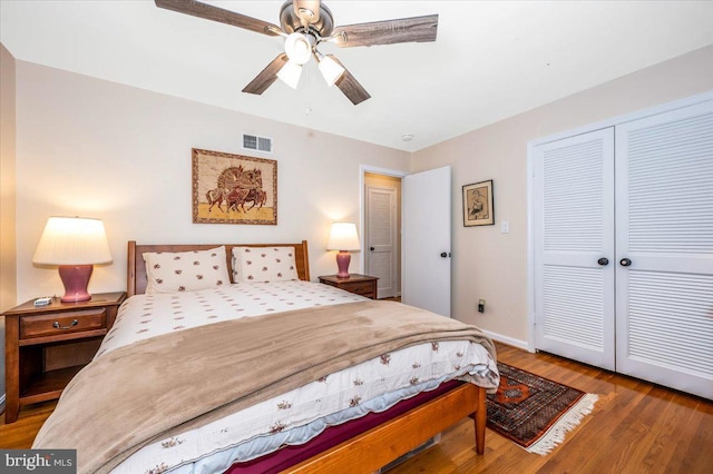 bedroom featuring baseboards, visible vents, ceiling fan, wood finished floors, and a closet