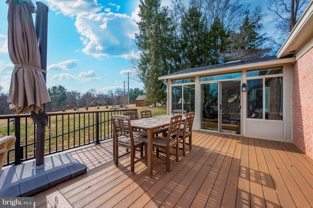 wooden deck featuring a sunroom and outdoor dining area