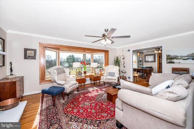 living area featuring ornamental molding, a ceiling fan, baseboards, and wood finished floors