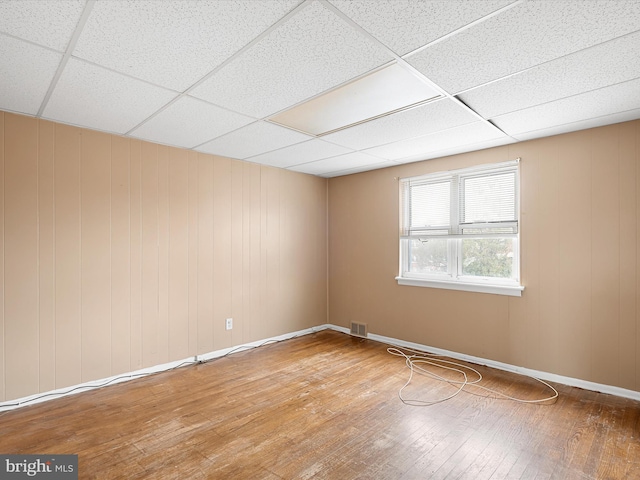 spare room with a drop ceiling and hardwood / wood-style flooring