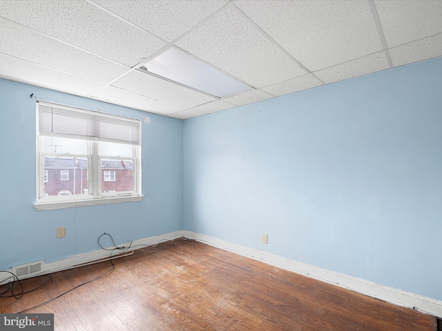 empty room with a drop ceiling and hardwood / wood-style floors