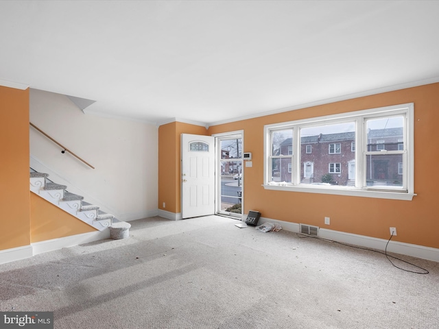 entrance foyer with crown molding and carpet