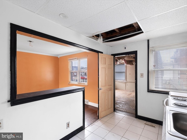 kitchen featuring a drop ceiling, sink, crown molding, and tile patterned floors