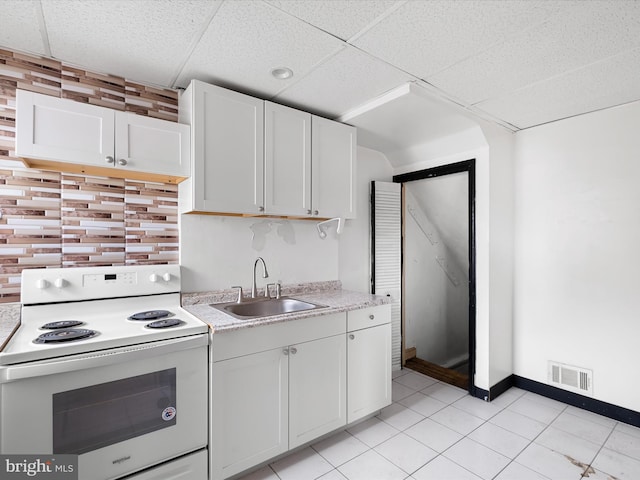 kitchen featuring a paneled ceiling, sink, white cabinets, light tile patterned floors, and white range with electric cooktop