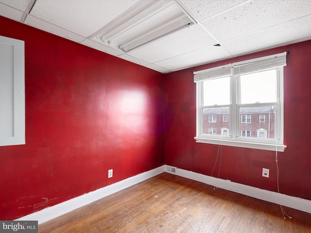 unfurnished room with wood-type flooring and a paneled ceiling