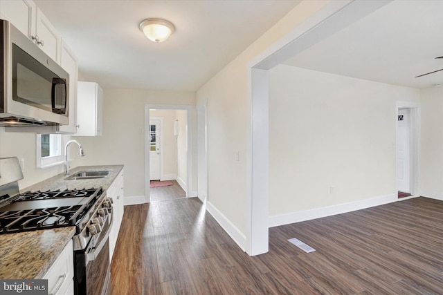 kitchen with sink, dark wood-type flooring, appliances with stainless steel finishes, light stone countertops, and white cabinets