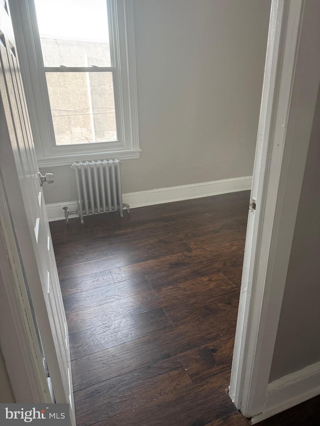 spare room with dark wood-type flooring and radiator heating unit