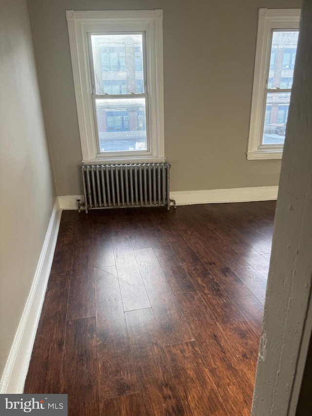 empty room featuring radiator and dark hardwood / wood-style flooring