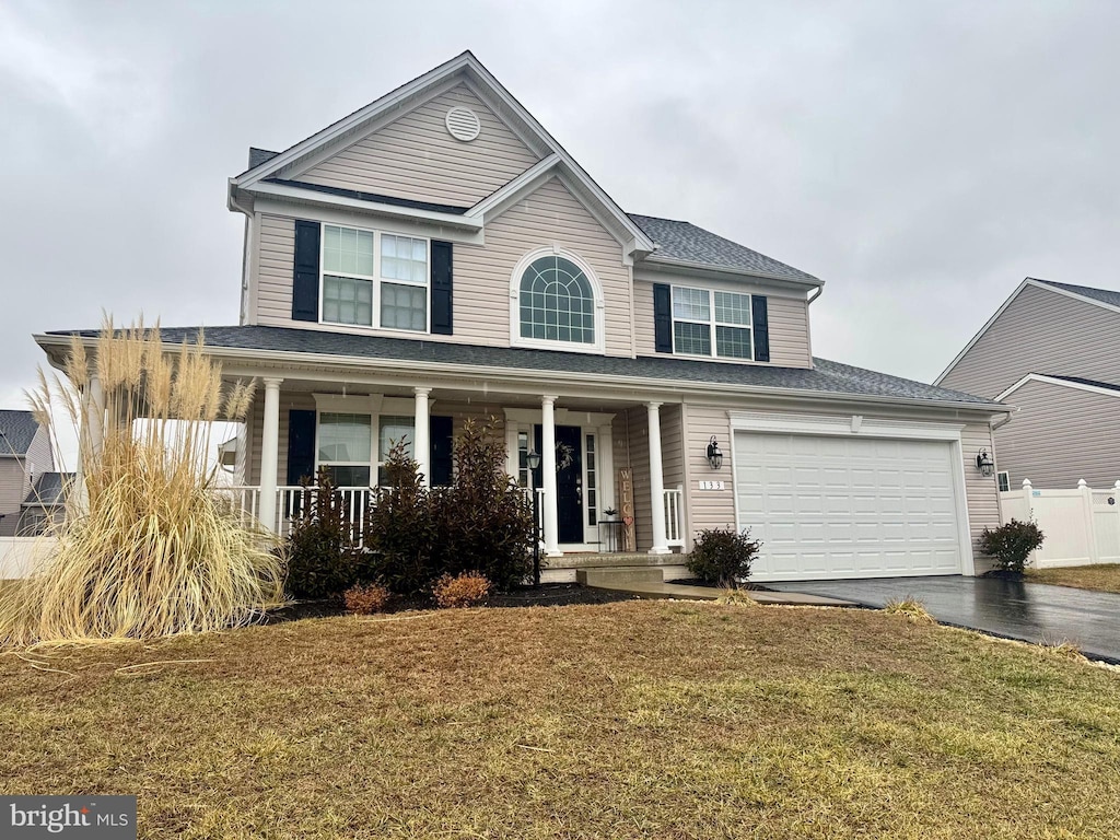 view of front facade with a garage, a front lawn, and covered porch