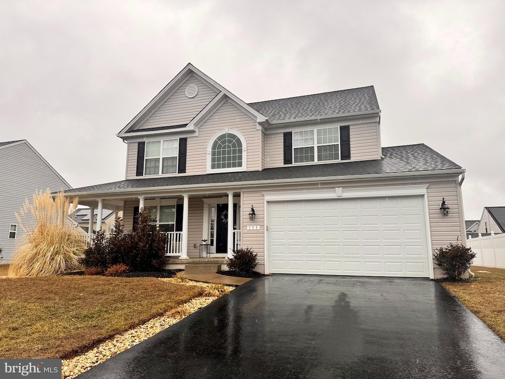 view of front facade featuring a porch, a garage, and a front yard