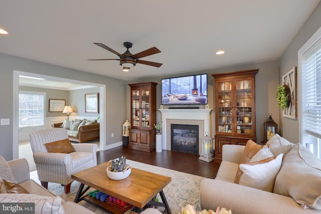 living room featuring ceiling fan, dark hardwood / wood-style floors, and a fireplace