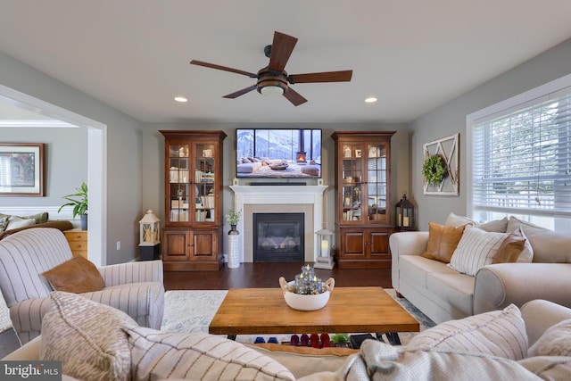 living room with ceiling fan, dark hardwood / wood-style floors, and a tile fireplace