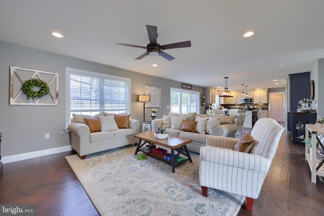 living room featuring dark wood-type flooring and ceiling fan