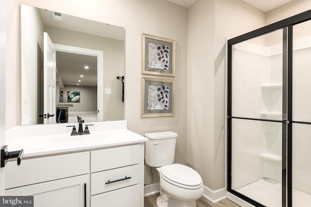 bathroom featuring vanity, an enclosed shower, and toilet