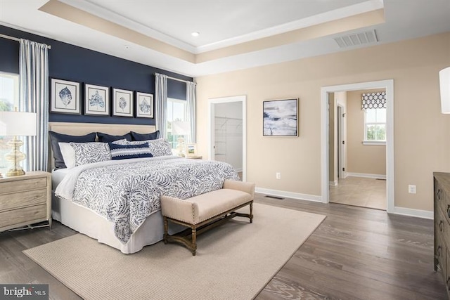 bedroom with dark wood-type flooring and a tray ceiling