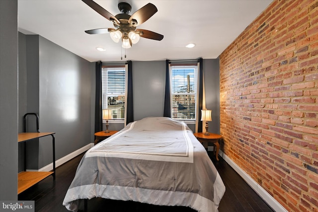 bedroom with ceiling fan, brick wall, and dark hardwood / wood-style floors