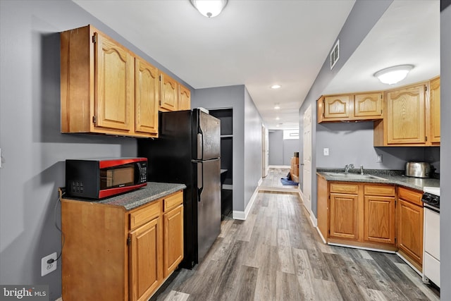 kitchen featuring hardwood / wood-style flooring, sink, white range, and black refrigerator