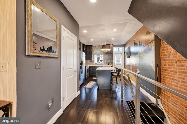 kitchen with pendant lighting, backsplash, dark hardwood / wood-style floors, a center island, and a kitchen bar