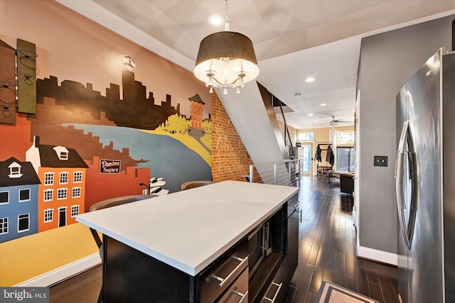 kitchen with a center island, stainless steel refrigerator, dark hardwood / wood-style floors, pendant lighting, and ceiling fan with notable chandelier