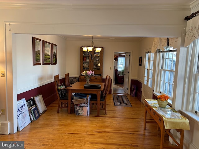 dining space featuring a notable chandelier, crown molding, and light wood-type flooring