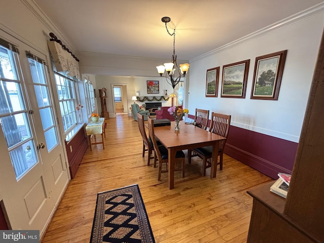 dining space with crown molding, an inviting chandelier, and light wood-type flooring