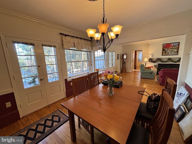 dining room featuring crown molding, an inviting chandelier, light hardwood / wood-style floors, and french doors