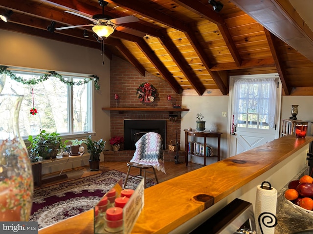 living room with a brick fireplace, plenty of natural light, lofted ceiling with beams, and wooden ceiling