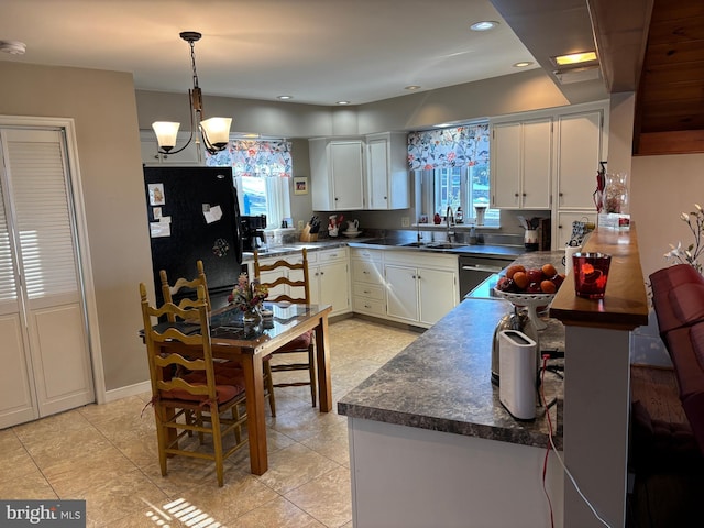 kitchen featuring white cabinetry, black refrigerator, sink, and a wealth of natural light