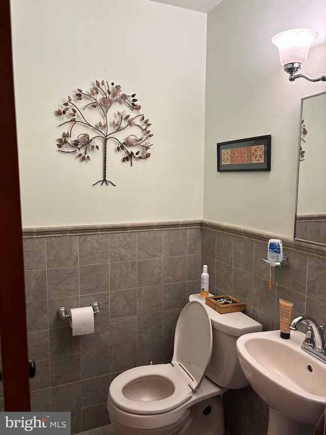 bathroom with sink, tile walls, and toilet