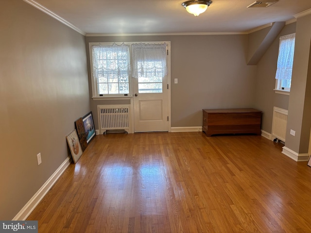 entryway with radiator, crown molding, and light wood-type flooring