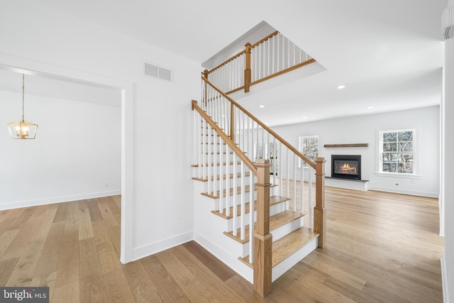 stairs featuring wood-type flooring and a chandelier