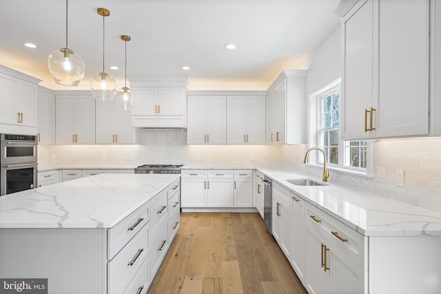 kitchen featuring pendant lighting, sink, appliances with stainless steel finishes, white cabinetry, and a kitchen island