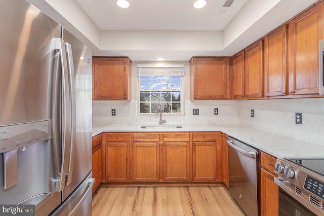 kitchen featuring stainless steel appliances, light hardwood / wood-style floors, sink, and decorative backsplash